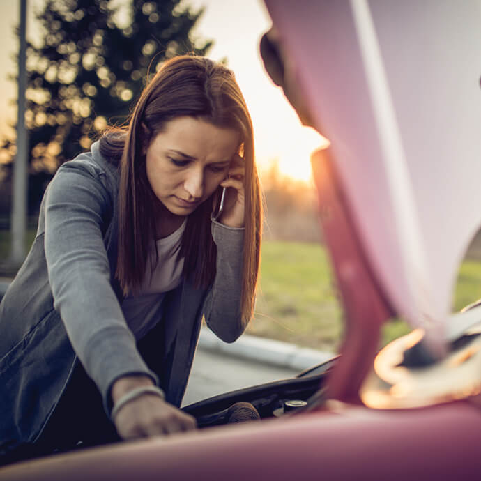 Woman investigates car trouble under the hood of her car