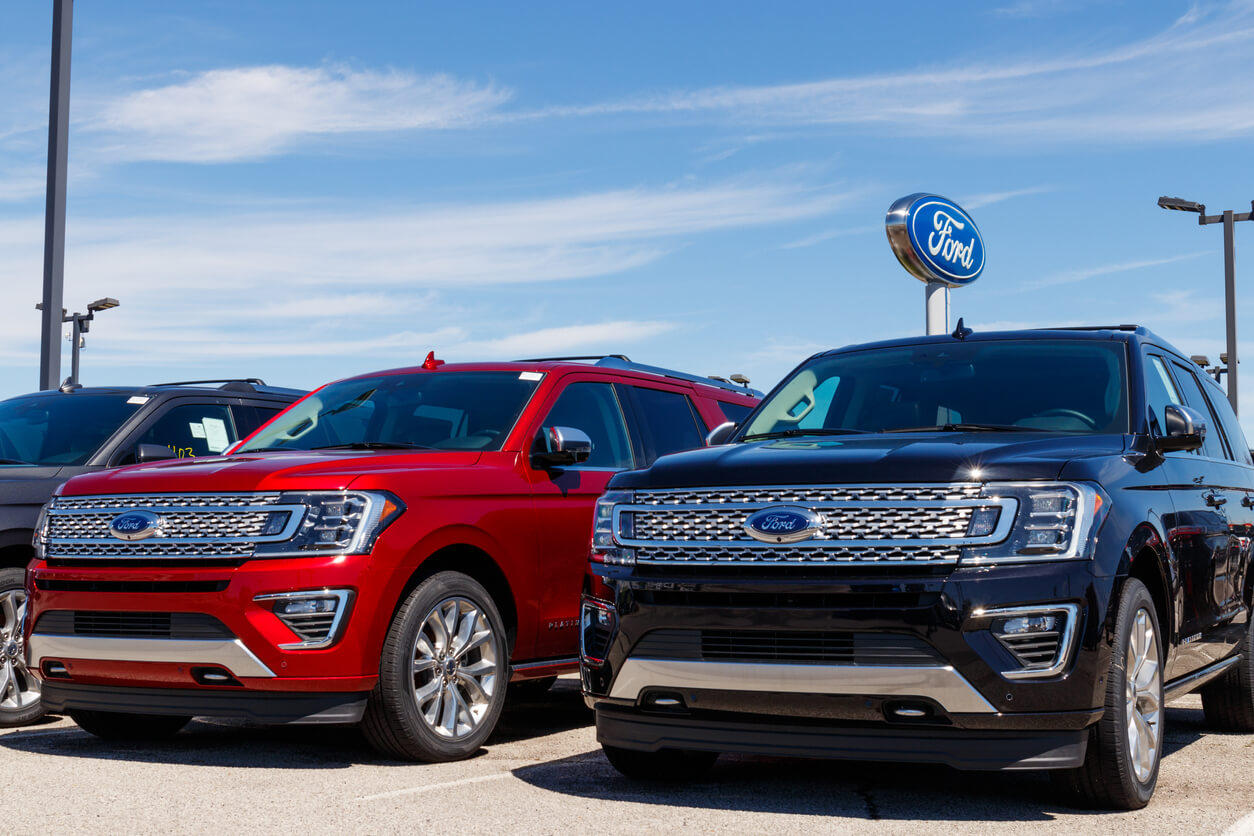 Ford SUVs and trucks in dealership parking lot.